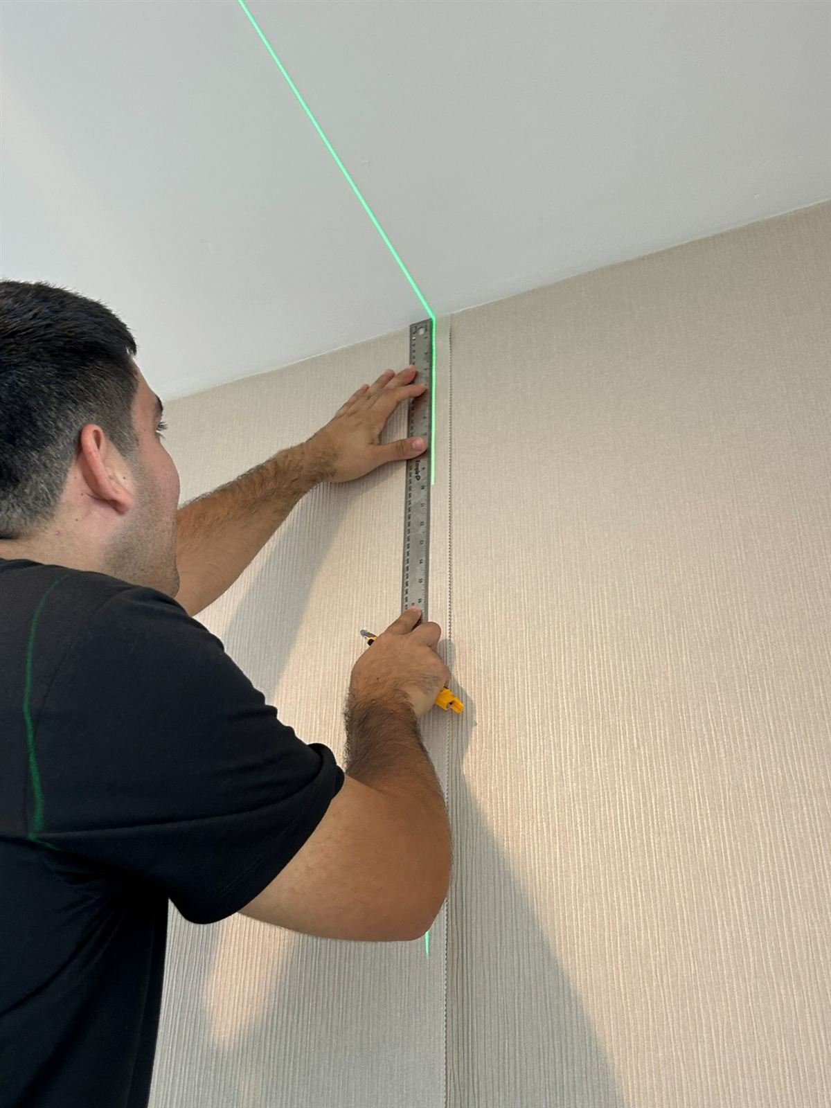 Wallpaper Group installer precisely measuring a wall on site